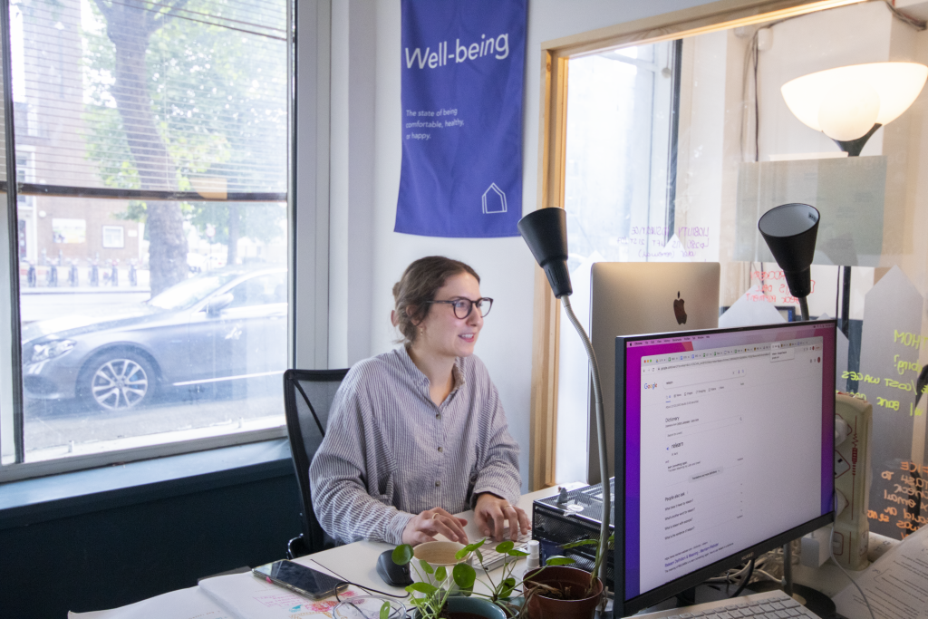 A woman working inside a private studio at Mainyard Studios, surrounded by natural light and indoor plants.