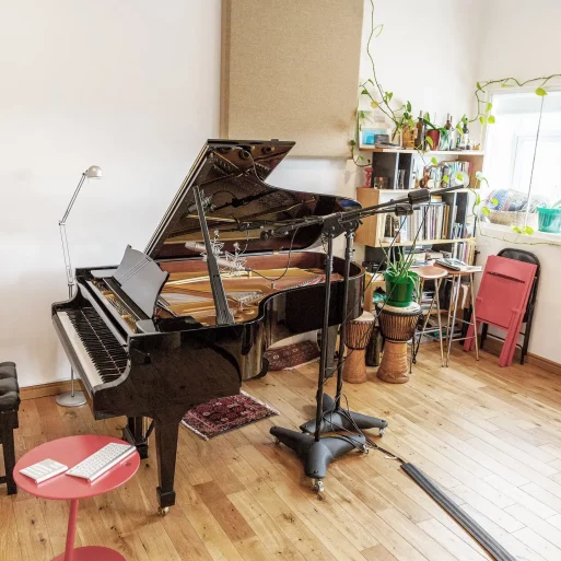 Bright soundproof studio with luxurious grand piano and professional audio recording equipment at Mainyard Studios, London.
